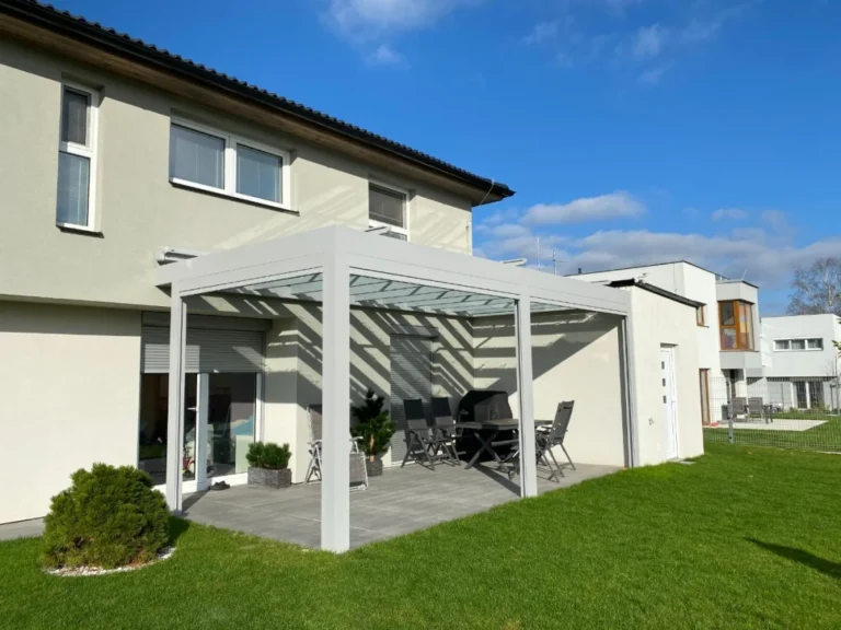 Bílá pergola s lamelovou střechou u rodinného domu