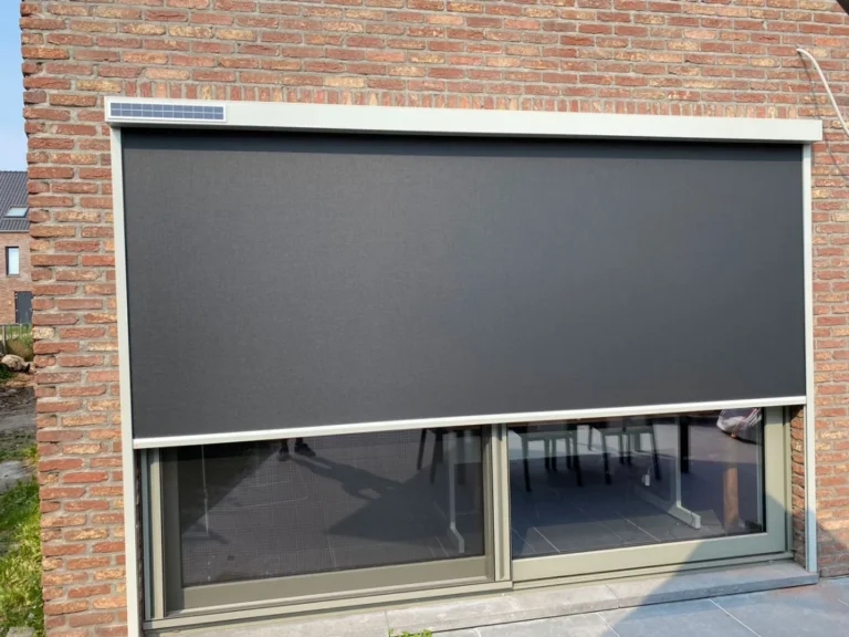 Tmavá screenová roleta na širokém okně cihlového domu